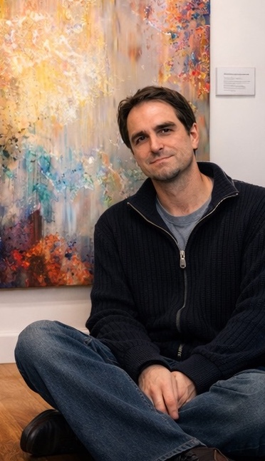 Abstract artist and art blog creator Jaison Cianelli sitting in front of painting A Heart So Big.